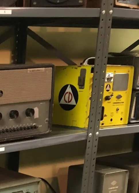 Rack of old radio equipment showing a yellow Gonset Communicator